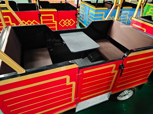 The red body, adorned with gold lines and retro geometric patterns, replicates the silhouette of an old-fashioned circus wagon; the cabin features an open design with built-in small tables, making it highly recognizable.